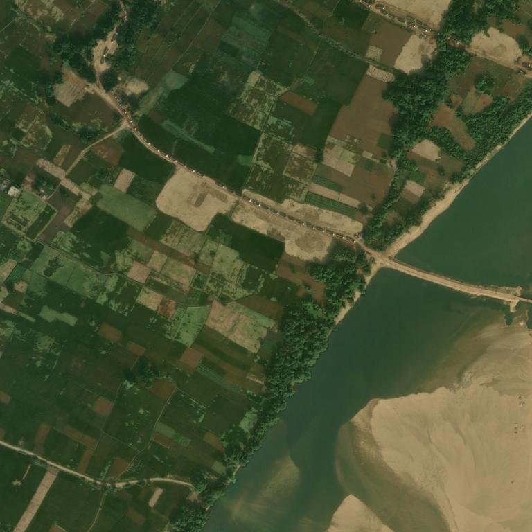 High-resolution view of a causeway built into the Son's channel, with trucks queued on the road to it